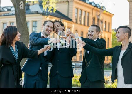 Glückliche Freunde, die während der Hochzeitszeremonie Sektflöten zum Anstoßen anheben Stockfoto