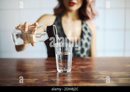 Frau gießt Wasser in Glas Stockfoto