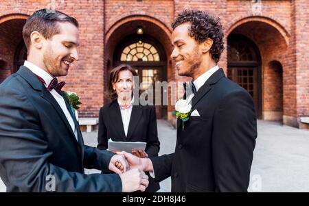 Priest Blick auf Mann hält Homosexuell Partner die Hand während der Hochzeit Zeremonie Stockfoto