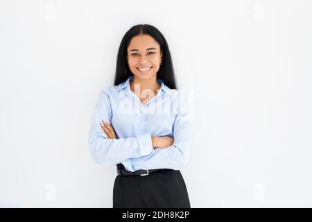 Lächelnd zuversichtlich schwarze Geschäftsfrau mit gekreuzten Armen posiert auf weiß Hintergrund Stockfoto