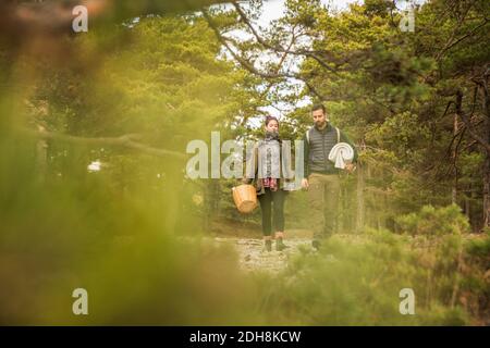 Paar mit Decke und Korb im Wald durch Pflanzen gesehen Stockfoto