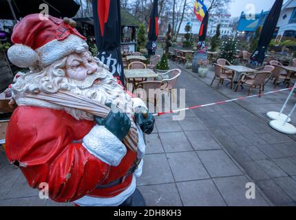 Boltenhagen, Deutschland. Dezember 2020. Die Figur des Weihnachtsmannes steht vor einem geschlossenen Restaurantbereich an der Strandpromenade. Aufgrund der teilweisen Coronasperre sind Hotels, Restaurants und touristische Einrichtungen an der Ostseeküste in Mecklenburg-Vorpommern geschlossen. Quelle: Jens Büttner/dpa-Zentralbild/dpa/Alamy Live News Stockfoto