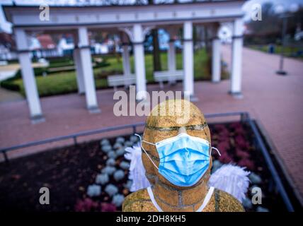 Boltenhagen, Deutschland. Dezember 2020. Unbekannte haben die Steinfigur an der Strandpromenade mit Engelsflügeln und einem Mund-und-Nase-Wächter ausgestattet. Aufgrund der teilweisen Coronasperre sind Hotels, Restaurants und touristische Einrichtungen an der Ostseeküste in Mecklenburg-Vorpommern geschlossen. Quelle: Jens Büttner/dpa-Zentralbild/dpa/Alamy Live News Stockfoto