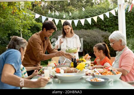 Familie, die im Sommer zusammen draußen isst Stockfoto