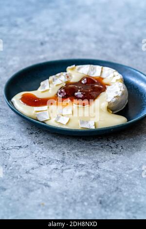 Gebackenes Brie-Käse-Dessert mit Erdbeermarmelade. Marmelade Geschmolzen Camembert. Traditionelles Bio-Dessert. Stockfoto