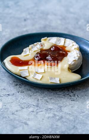 Gebackenes Brie-Käse-Dessert mit Erdbeermarmelade. Marmelade Geschmolzen Camembert. Traditionelles Bio-Dessert. Stockfoto