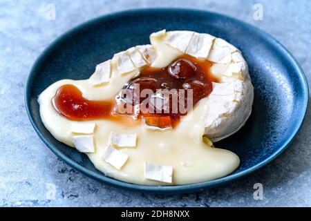 Gebackenes Brie-Käse-Dessert mit Erdbeermarmelade. Marmelade Geschmolzen Camembert. Traditionelles Bio-Dessert. Stockfoto