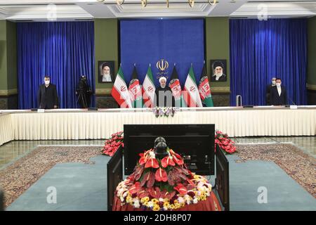 Teheran, Iran. Dezember 2020. Auf diesem Foto, das von der offiziellen Website des Büros der iranischen Präsidentschaft veröffentlicht wurde, steht Präsident Hassan Rohani zu Beginn einer Videokonferenz mit seinem afghanischen Amtskollegen, um die erste Eisenbahnverbindung zwischen den beiden Ländern zu eröffnen, im Präsidentenpalast in Teheran, Iran, Donnerstag, den 10. Dezember, 2020. Die 140 Kilometer lange (90 Meilen) lange Strecke vom östlichen Iran nach Westafghan wird schließlich auf die afghanische Stadt Herat ausgeweitet und stellt eine wichtige Verkehrsverbindung für das Binnenland dar. (Bild: © Iranischer Ratsvorsitz via ZUM Stockfoto