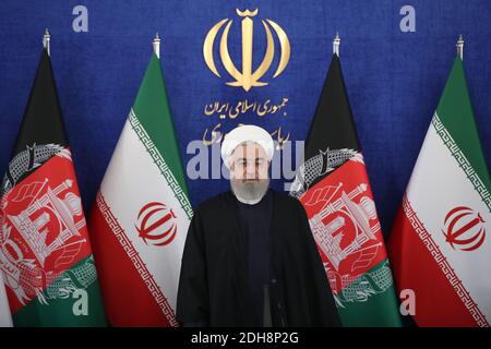 Teheran, Iran. Dezember 2020. Auf diesem Foto, das von der offiziellen Website des Büros der iranischen Präsidentschaft veröffentlicht wurde, steht Präsident Hassan Rohani zu Beginn einer Videokonferenz mit seinem afghanischen Amtskollegen, um die erste Eisenbahnverbindung zwischen den beiden Ländern zu eröffnen, im Präsidentenpalast in Teheran, Iran, Donnerstag, den 10. Dezember, 2020. Die 140 Kilometer lange (90 Meilen) lange Strecke vom östlichen Iran nach Westafghan wird schließlich auf die afghanische Stadt Herat ausgeweitet und stellt eine wichtige Verkehrsverbindung für das Binnenland dar. (Bild: © Iranischer Ratsvorsitz via ZUM Stockfoto