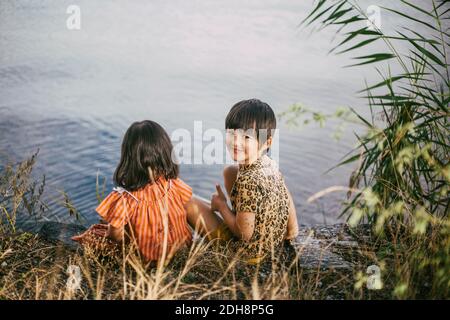 Portrait von lächelndes Mädchen mit Down-Syndrom Schwester sitzt in der Nähe see Stockfoto