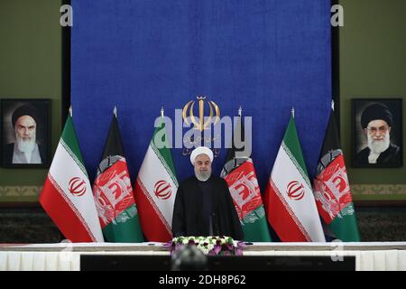 Teheran, Iran. Dezember 2020. Auf diesem Foto, das von der offiziellen Website des Büros der iranischen Präsidentschaft veröffentlicht wurde, steht Präsident Hassan Rohani zu Beginn einer Videokonferenz mit seinem afghanischen Amtskollegen, um die erste Eisenbahnverbindung zwischen den beiden Ländern zu eröffnen, im Präsidentenpalast in Teheran, Iran, Donnerstag, den 10. Dezember, 2020. Die 140 Kilometer lange (90 Meilen) lange Strecke vom östlichen Iran nach Westafghan wird schließlich auf die afghanische Stadt Herat ausgeweitet und stellt eine wichtige Verkehrsverbindung für das Binnenland dar. (Bild: © Iranischer Ratsvorsitz via ZUM Stockfoto