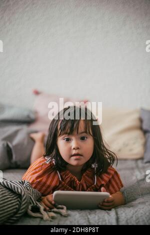 Portrait von Down-Syndrom Mädchen mit digitalen Tablet beim Liegen Auf dem Sofa zu Hause Stockfoto