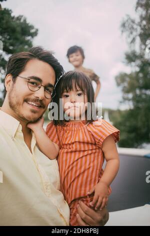 Porträt eines lächelnden Vater trägt sich Syndrom Tochter gegen stehen Mädchen auf Trampolin im Sommer Stockfoto