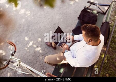 Blick aus der Höhe des Geschäftsmannes mit Laptop während des Sitzens parkbank Stockfoto