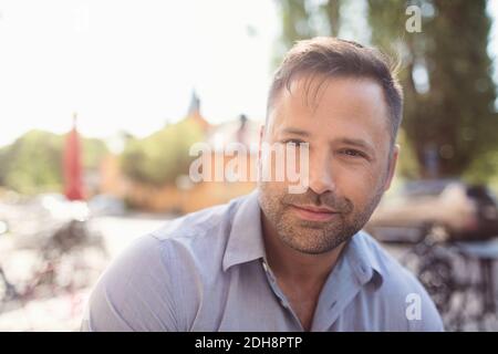 Porträt eines selbstbewussten Geschäftsmannes, der Musik über in-Ear-Kopfhörer hört Sonniger Tag Stockfoto