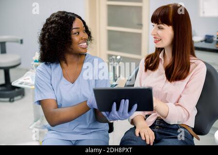 Zahnmedizin, Mundpflege, Zahnaufhellung Konzept. Ziemlich lächelnd junge zufrieden kaukasischen Frau sitzt in Zahnarztstuhl und Blick auf ihre Frau Stockfoto