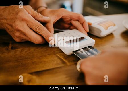 Zugeschnittene Hand des Kunden, der den Besitzer mit Kreditkarte bezahlt Café-Bar Stockfoto