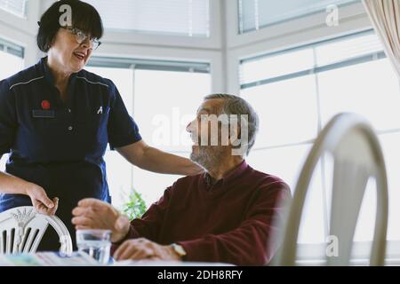Älterer Mann im Gespräch mit der Hausmeisterin zu Hause Stockfoto