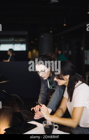 Seitenansicht von weiblichen Profis, die im Büro an einem Laptop arbeiten Stockfoto