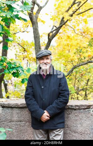 Porträt eines glücklichen älteren Mannes, der im Herbst im Park steht Stockfoto