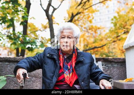 Porträt einer selbstbewussten älteren Frau, die im Herbst im Park sitzt Stockfoto