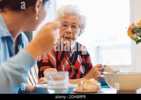 Ältere Frau im Gespräch mit Tochter, während sie zu Hause essen Stockfoto