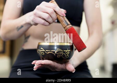 Nahaufnahme einer nicht erkennbaren Frau, die mit einer tibetischen Schale Klang macht. Entspannungskonzept. Stockfoto