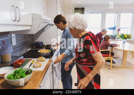 Seitenansicht der älteren Frau und Tochter, die Essen kochen Küche Stockfoto