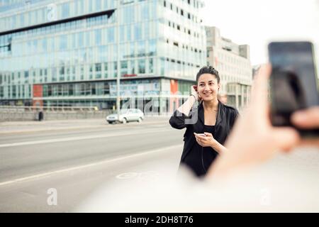 Zugeschnittenes Bild einer Frau, die eine Freundin in der Stadt fotografiert Stockfoto