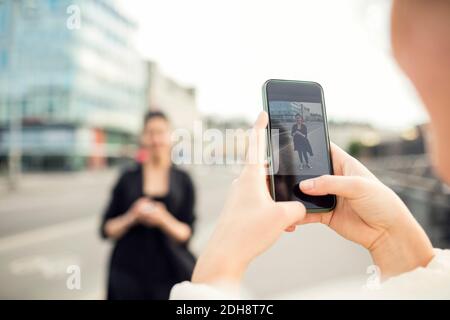 Zugeschnittenes Bild einer Frau, die einen Freund in der Stadt fotografiert Stockfoto