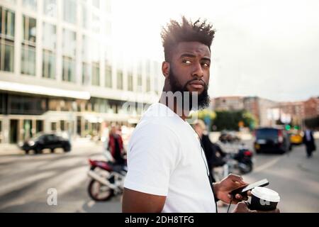 Mann mit Handy und Kaffeetasse in der Stadt Stockfoto