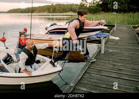 Die Familie schaute während der Fahrt auf die Frau, die auf dem Pier vom Boot sprang Sommer Stockfoto