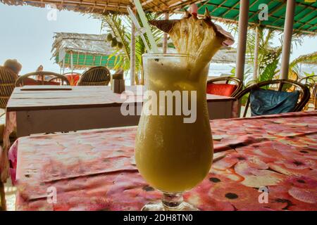 Pina Colada Cocktail mit Ananasgarnitur und einem Plastikstroh auf einem Tisch in einer exotischen Location in Goa, Indien. Stockfoto