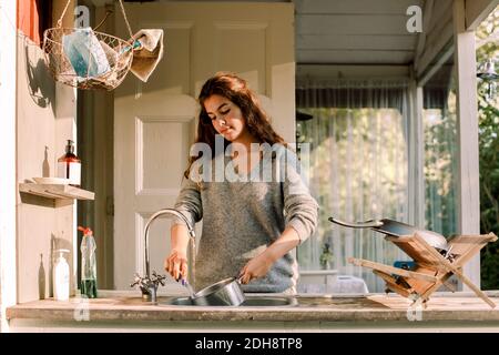 Teenager-Mädchen Waschutensilien im Waschbecken außerhalb des Hauses Stockfoto