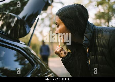 Seitenansicht der Frau, die Lippenstift beim Blick im Auto Angezeigt Stockfoto