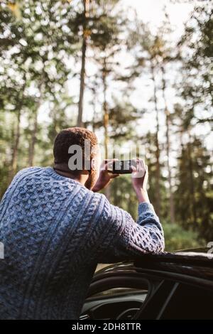 Rückansicht des Menschen, der mit dem Auto durch das Smartphone fotografiert Während der Ferien Stockfoto