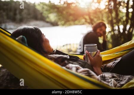 Seitenansicht der Frau mit Freund auf Hängematte im Wald Stockfoto