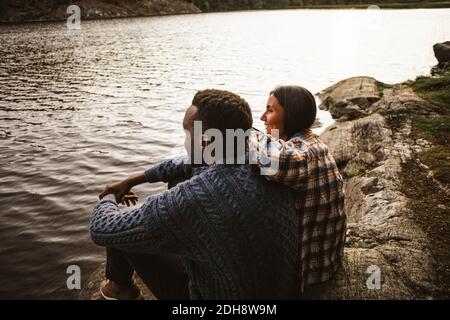 Seitenansicht des Mannes und der Frau, die am See sitzen Wald Stockfoto