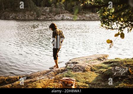 Junger Mann, der während des Urlaubs am See im Wald steht Stockfoto