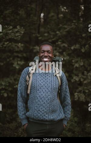 Porträt eines lächelnden Mannes mit Händen in den Taschen im Wald Stockfoto