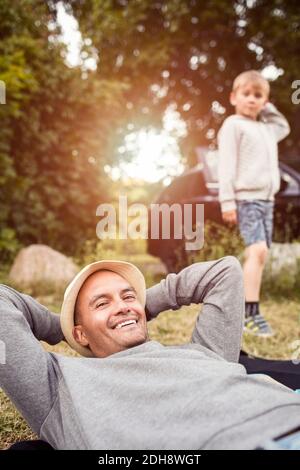 Portrait von glücklichen Mann entspannen mit Jungen im Hintergrund stehen Im Park Stockfoto