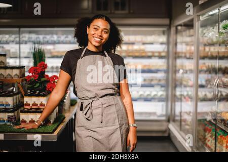 Porträt einer lächelnden Verkäuferin, die im Supermarkt steht Stockfoto