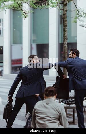 Rückansicht der Unternehmer begrüßen einander mit Ellenbogen Beule In der Stadt Stockfoto