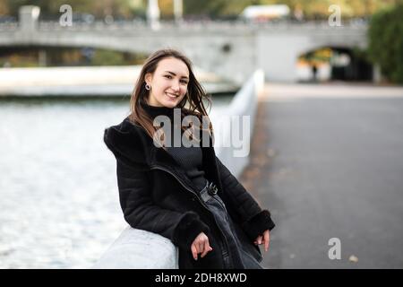 Ein Mädchen steht auf dem Damm in der Nähe des Wassers, in warmen Kleidern. Stockfoto