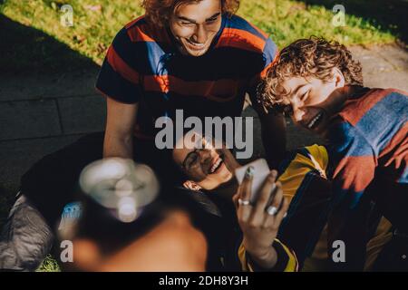 Fernsicht von lächelnden männlichen Freunden mit dem Handy Im öffentlichen Park Stockfoto