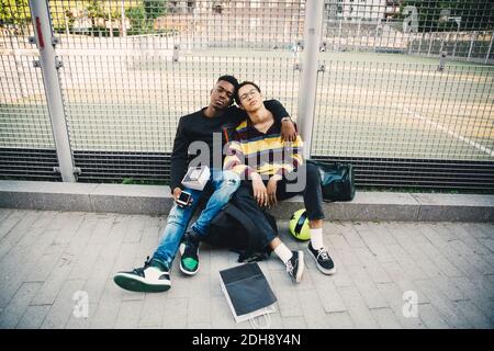 Ganzkörperportrait von jungen Mann mit Freund sitzend gegen Netto Stockfoto