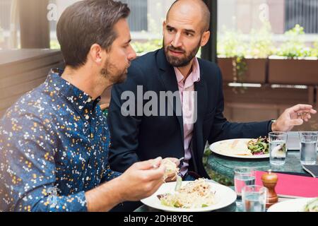 Geschäftsleute mit mittlerem Erwachsenenalter diskutieren beim Mittagessen im Bürohof Stockfoto