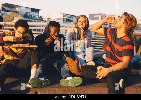 Junge und Teenager männliche Freunde essen Pizza im Hafen in Stadt Stockfoto