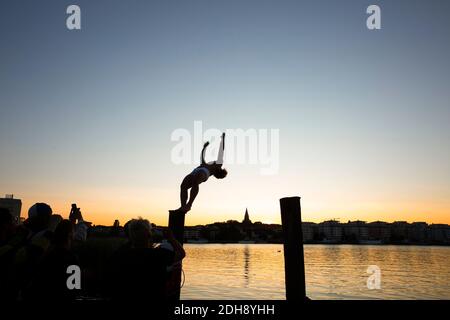 Junger Mann dreht zurück, während Freunde am See während des Sonnenuntergangs fotografieren Stockfoto