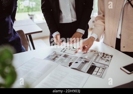 Mittelteil der Frau zeigt auf Magazin von Immobilienmakler Im neuen Haus Stockfoto